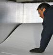 A contractor installing TerraBlock™ floor insulation in a Rochester crawl space