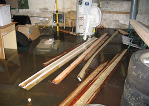 A severely flooding basement in Rochester, with lumber and personal items floating in a foot of water