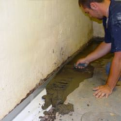 A basement waterproofer installing a perimeter drain system in Ocean Shores