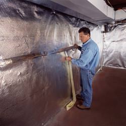 Installation of a radiant heat and vapor barrier on a basement wall in Montesano